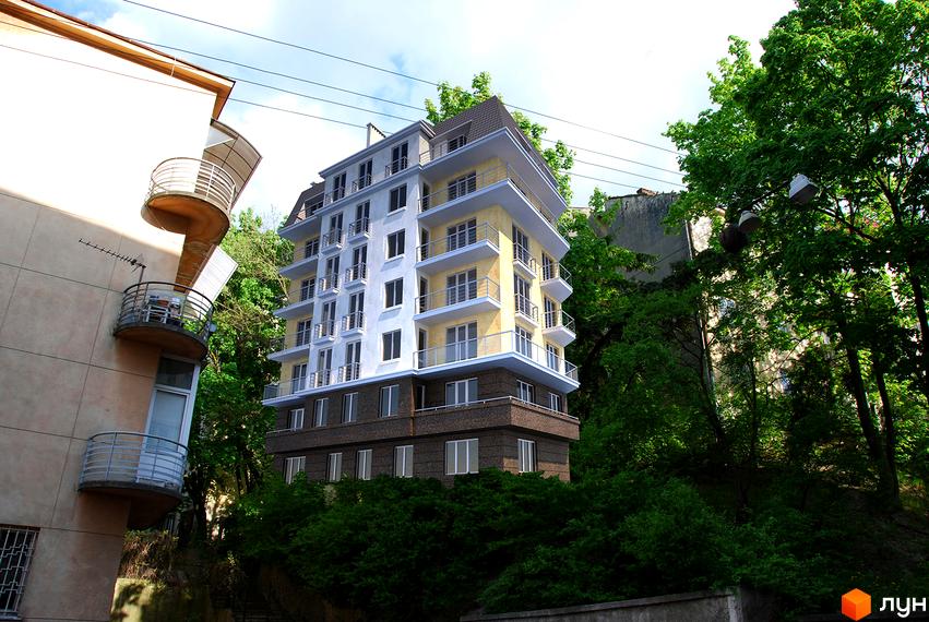 Новобудова на вул. Тарнавського, 48: багатоповерховий будинок зі світлими фасадами, жовтими та білими елементами, балконами та зеленими деревами навколо. Опис зовнішнього вигляду та прибудинкової території.