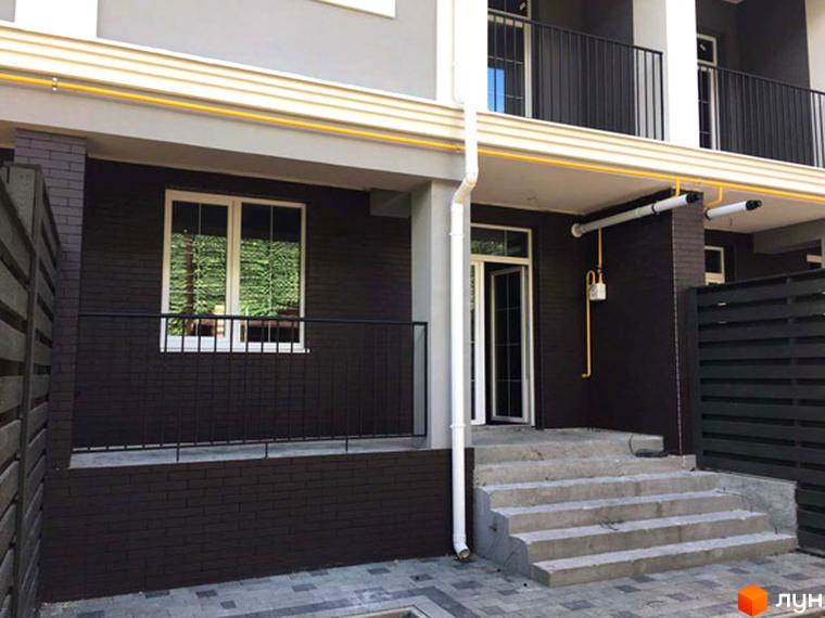 Зовнішній вигляд таунхаусу Pacific Park. Фасад будинку виконаний у темних тонах, є сходи до входу. На території бруківка та огорожа.