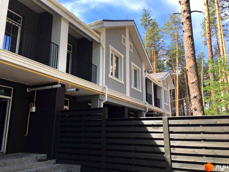 Таунхаус Pacific Park: сірі будинки з білим оздобленням та чорними балконами, розташовані біля соснового лісу за темним дерев'яним парканом.