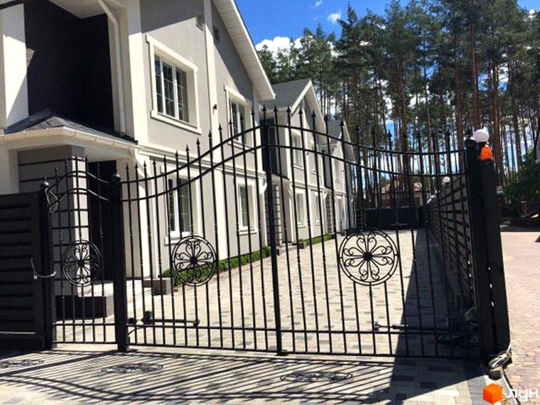 Фасад таунхаусу в ЖК „Pacific Park“ з кованими воротами та доглянутою прибудинковою територією. Огороджена територія з ландшафтним дизайном.