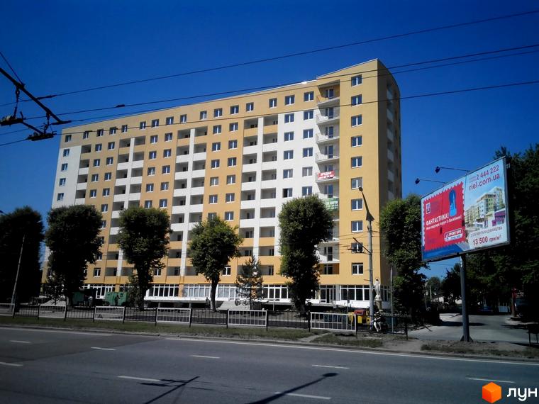 Зовнішній вигляд новобудови ЖК на Стрийській, 204. Будинок має жовто-білий фасад та багато вікон. Перед будинком розташована дорога та дерева.