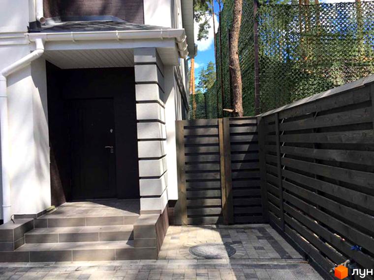 Вхідна група таунхаусу Pacific Park з темними дверима та сходами. Поруч розташована огороджена територія з дерев'яним парканом.