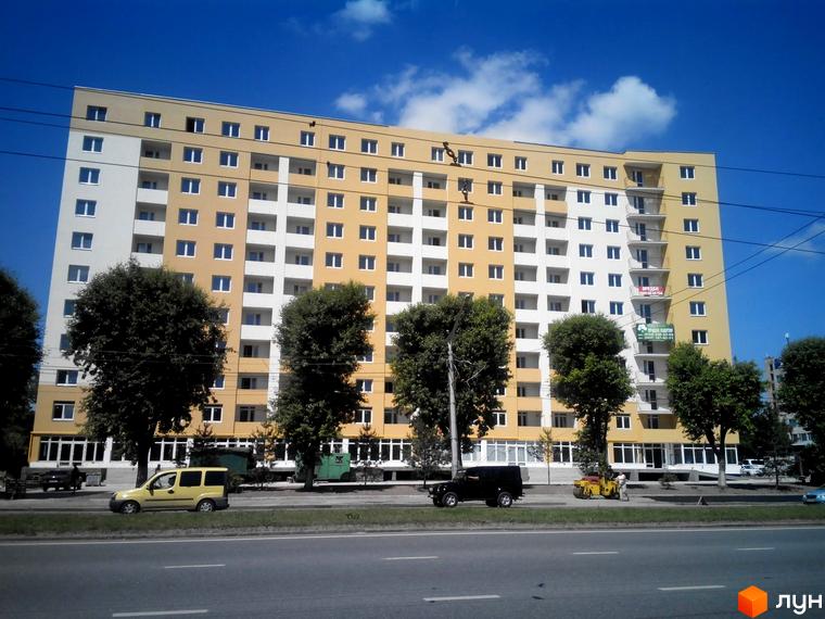 Новобудова на Стрийській, 204 - багатоповерховий будинок з жовто-білим фасадом та балконами. Перед будинком розташована дорога з автомобілями та деревами.