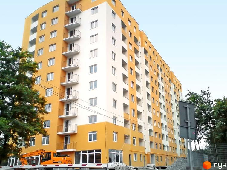 Новобудова ЖК на Стрийській, 204, має жовто-білий фасад та багато балконів. Біля будинку видно будівельну техніку та дерева.