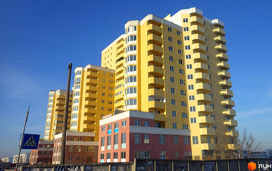 Житловий комплекс на вул. Євгена Харченка, 47-59, з жовтими фасадами та балконами. Прибудинкова територія з огорожею та дорожніми знаками.