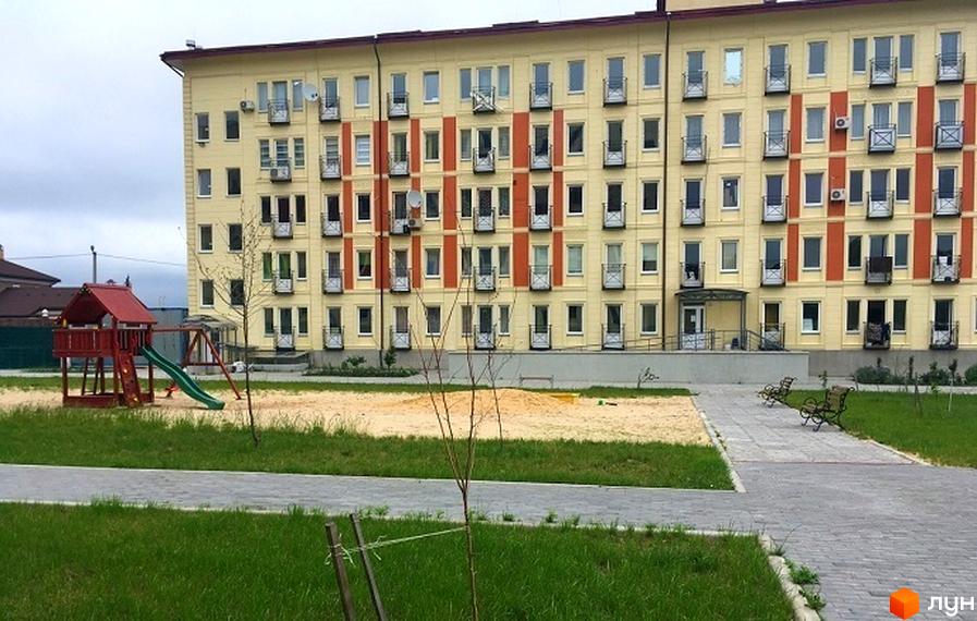 Житловий комплекс Кошовий: жовта багатоповерхівка з балконами та дитячим майданчиком. Зовнішній вигляд новобудови та прибудинкової території.