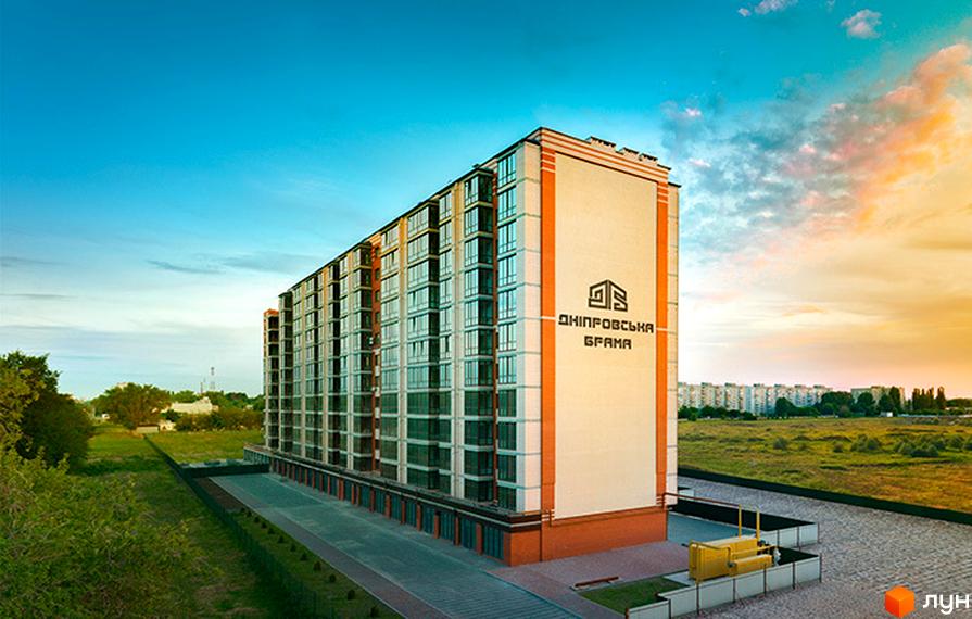 Висотна новобудова ЖК Дніпровська Брама з великими вікнами на тлі блакитного неба. Поряд з будинком розташована доглянута прибудинкова територія з газоном.