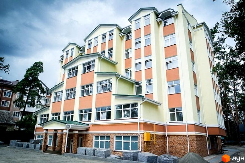 Зовнішній вигляд багатоповерхового будинку житлового комплексу на вул. Шевченка, 22б. Фасад оздоблений світлими та помаранчевими панелями, з великою кількістю вікон. Біля будинку видно будівельні матеріали та дерева.