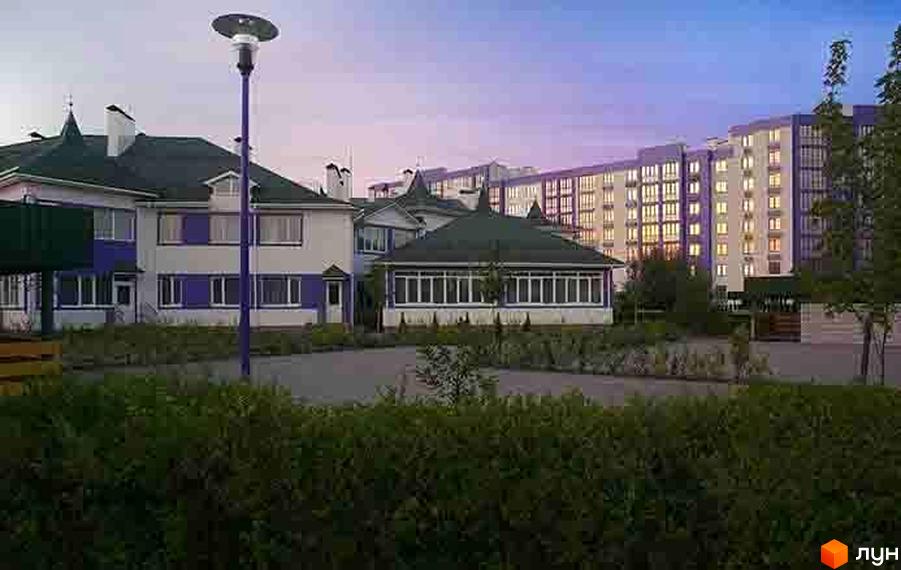 Житловий комплекс Аметист: двоповерхові будинки з фіолетовими елементами та багатоповерховий будинок на тлі. Прибудинкова територія з кущами та деревами.