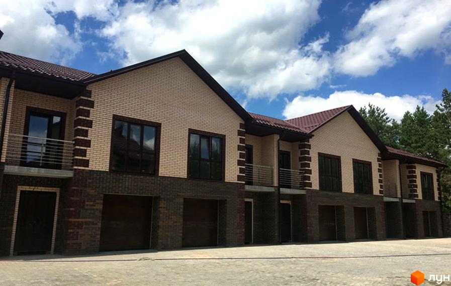 Зовнішній вигляд таунхаусів Green Villa з цегляним фасадом та темним дахом. Поруч розташована брукована ділянка.