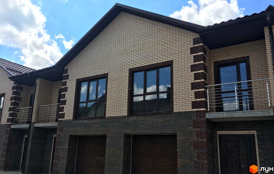 Фасад таунхаусів Green Villa облицьований світлою та темною цеглою. Великі вікна та гаражні ворота на першому поверсі.