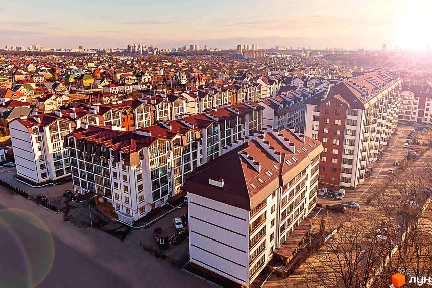 Житловий комплекс Празький квартал. Сучасні багатоповерхові будинки з коричневими дахами та великими вікнами. Прибудинкова територія з доглянутими деревами та парковкою.