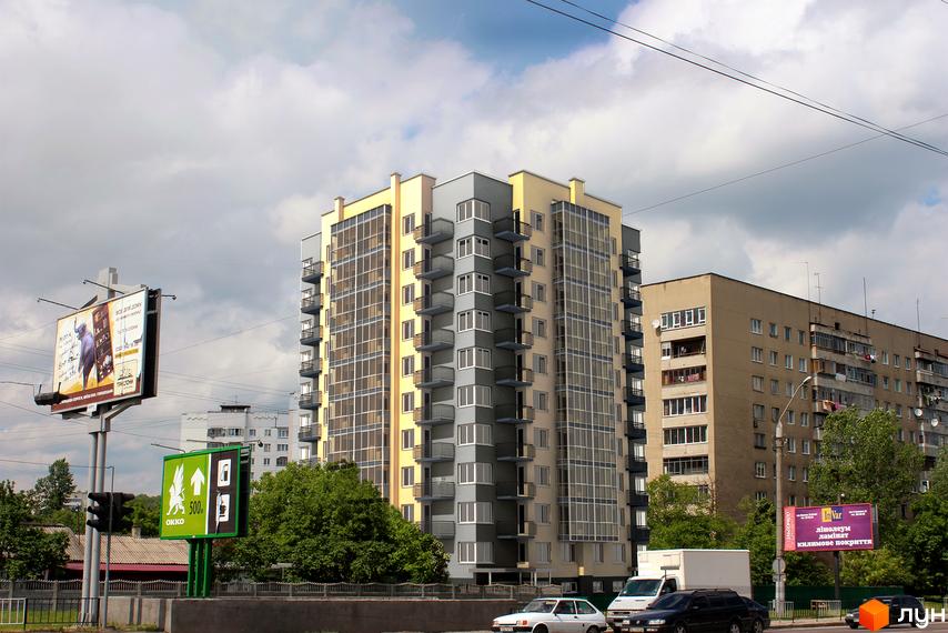 Висотна будівля Житловий комплекс Марко Поло з панорамними вікнами та балконами. На передньому плані розташовані рекламні щити та зелені насадження.