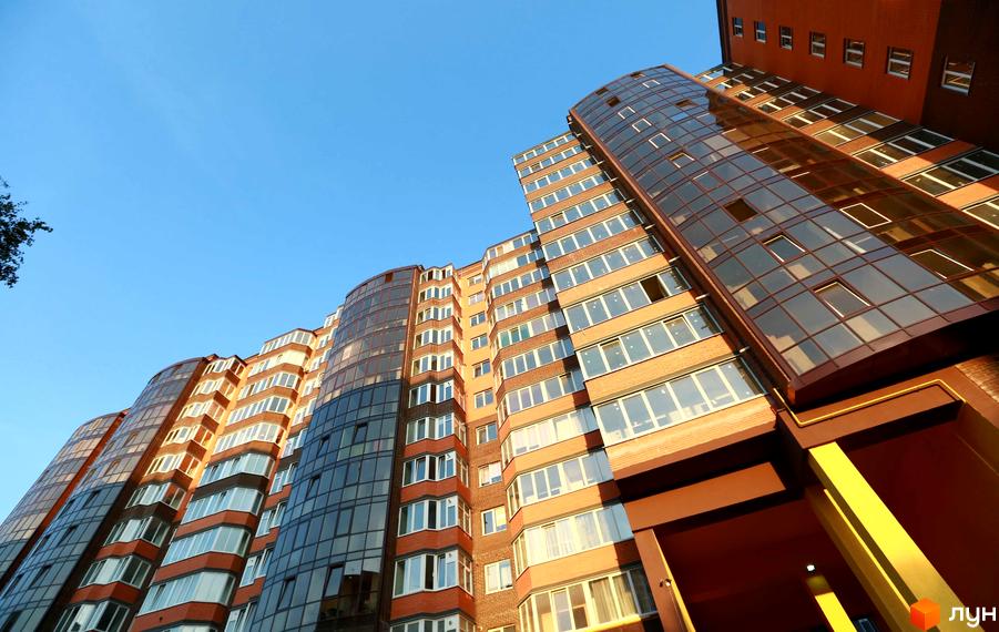 Новобудова Галицький Лев: багатоповерховий будинок з цегляними фасадами та великими скляними вікнами, що має вигнуті секції.