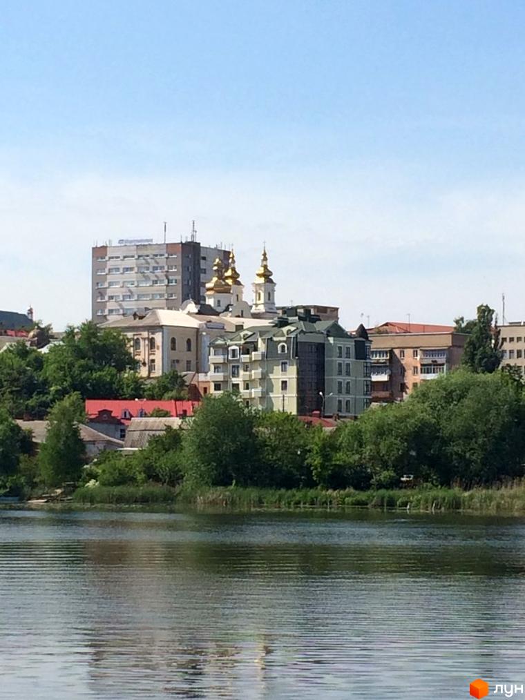 Житловий комплекс на вулиці Монастирська (Володарського) у Кам'янці-Подільському. Комплекс складається з багатоповерхових будинків з золотими куполами та зеленими насадженнями біля річки.