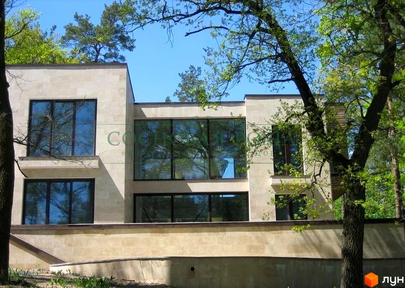 Будинок з великими вікнами в Котеджному містечку Соснова роща. Навколо будівлі ростуть дерева та зелені насадження.