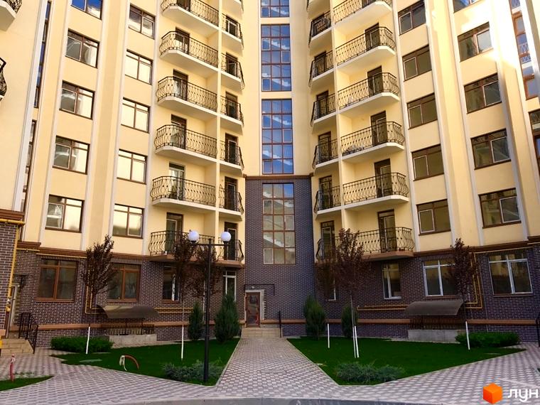Фасад житлового комплексу Rich Town з балконами та вікнами. Прибудинкова територія з газоном та доріжками.