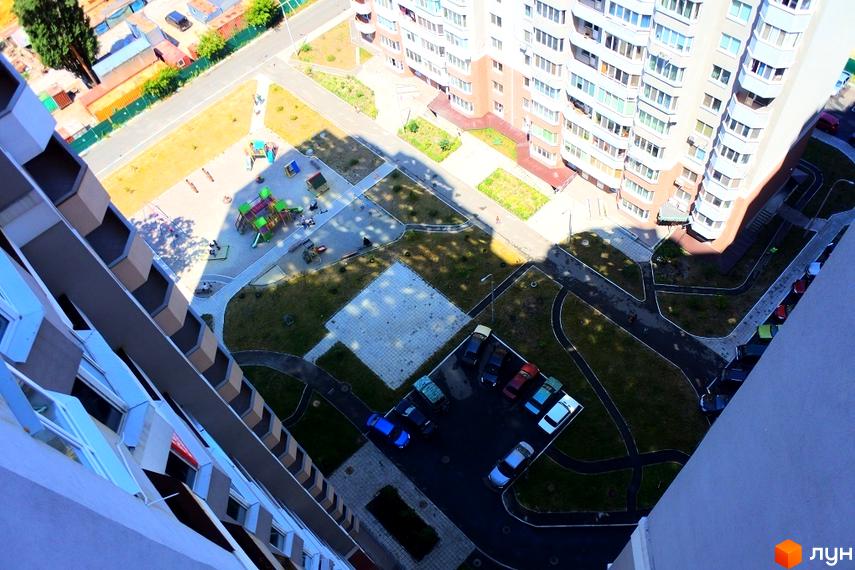 Житловий комплекс Коцюбинський: багатоповерховий будинок зі світлим фасадом, балконами. Двір має дитячий майданчик, зелені зони та парковку.