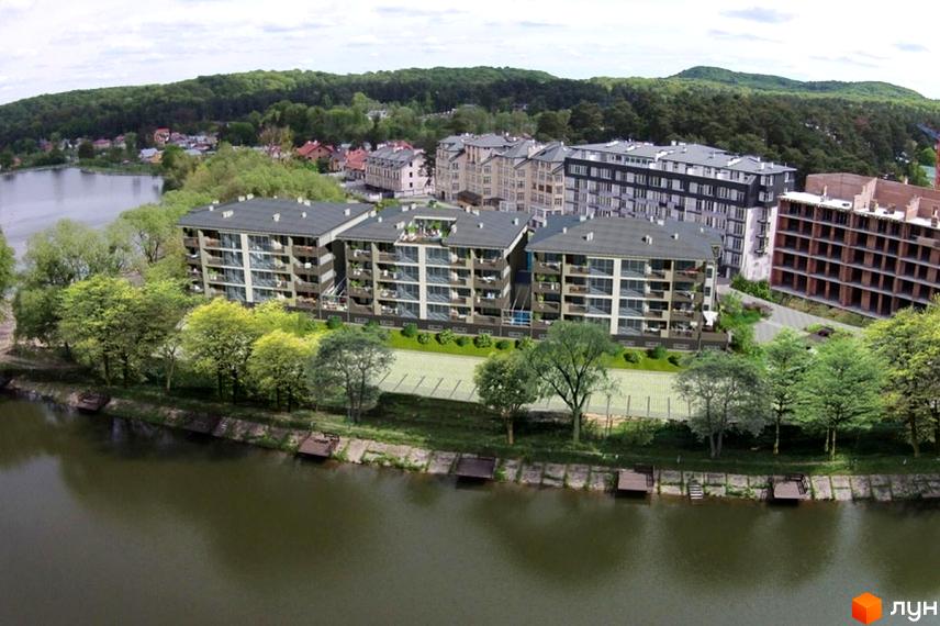 Житловий комплекс Хвиля Lux складається з кількох багатоповерхових будинків з балконами, розташованих біля річки серед зелені дерев.