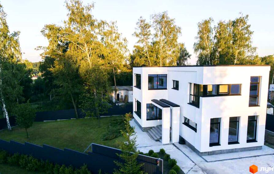 Білий будинок з чіткими лініями та темними вікнами в Котеджному містечку Barberry Park. Навколо зелений газон та високі дерева.