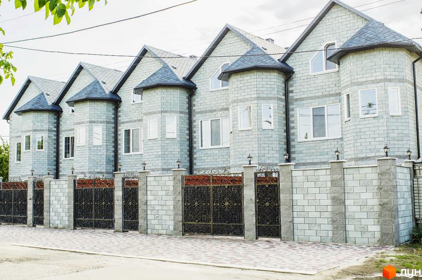 Зображення таунхаусів в Житловому комплексі „На Байкальській“. Фасад будинку з сірої цегли, темний дах, металева огорожа з цегляними стовпчиками.