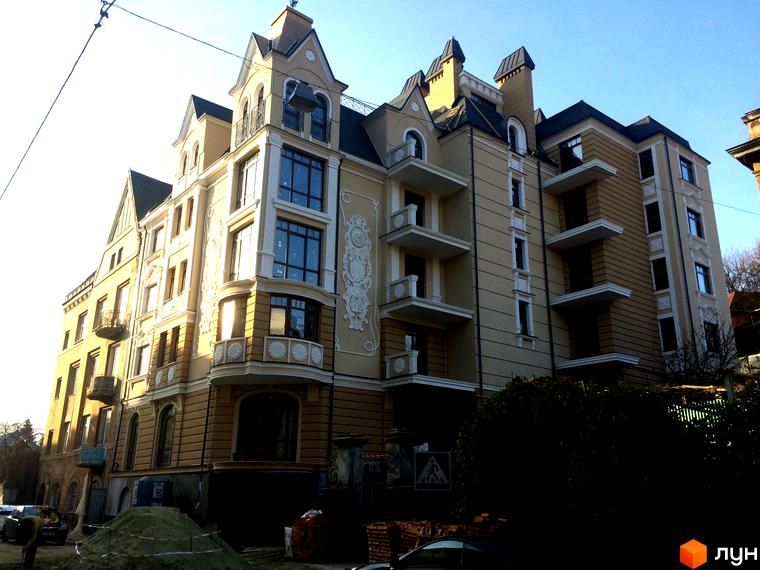 Фасад житлового комплексу на вулиці Лисенка, 57, з елементами декору та балконами. Навколо будинку видно будівельні роботи та зелені насадження.