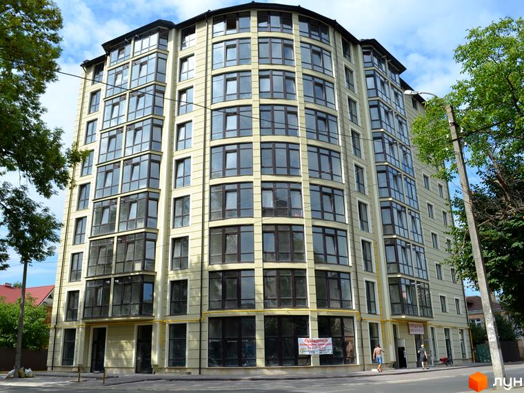 Фасад новобудови на вулиці Довга, 20в, з численними вікнами та балконами. Навколо будівлі видно дерева та елементи міської інфраструктури.