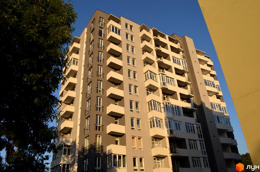 Будівельний проєкт на вул. Водогінна, 2. Багатоповерховий будинок з сірими та білими фасадами, балконами та великою кількістю вікон.