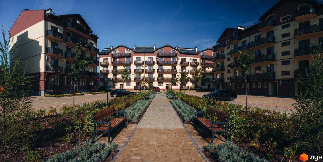 Житловий комплекс Едельвейс. Багатоквартирний будинок з балконами, оздоблений в світлих тонах. Доглянута прибудинкова територія з алеєю, лавками та зеленими насадженнями.