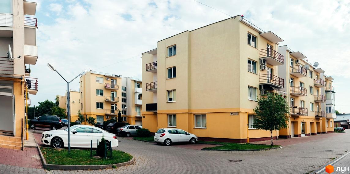 Житловий комплекс з балконами, розташований на вулиці Шевченка. На території комплексу є парковка для автомобілів та зелені насадження.