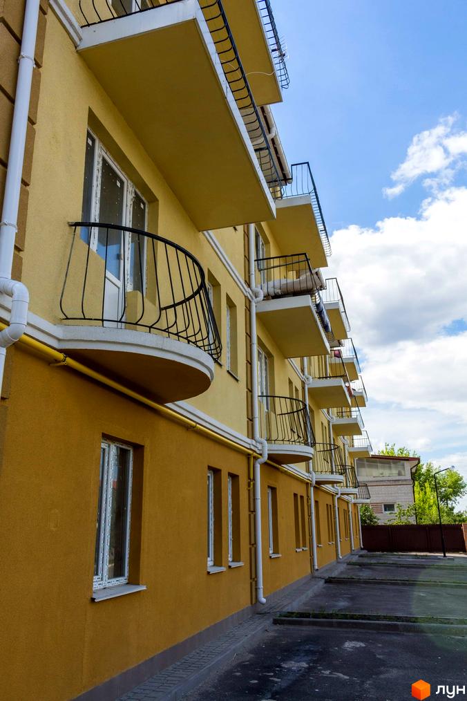 Житловий комплекс Вересковий з балконами та вікнами. На фото видно фасад будівлі, балкони з кованими огорожами та прибудинкову територію.