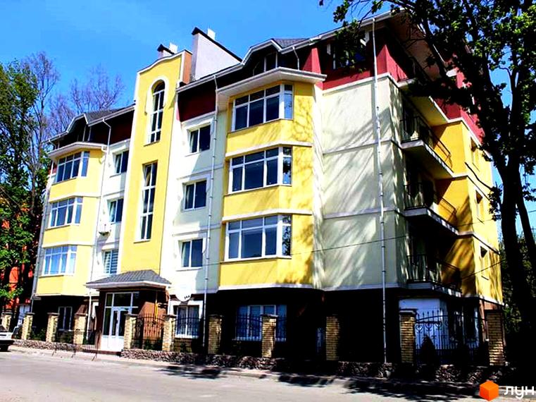 Багатоповерховий будинок ЖК Ваша квартира з жовтим фасадом та великими вікнами. Навколо будинку є кована огорожа та зелені насадження.