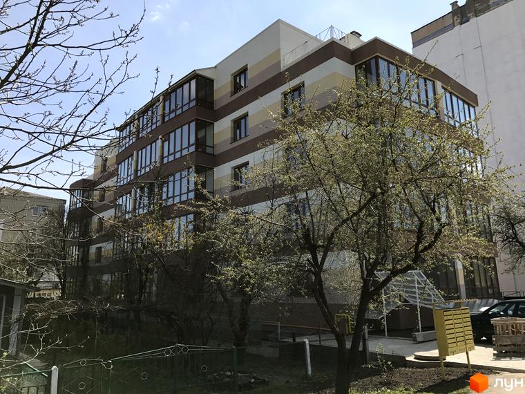 Житловий комплекс Будинок мрії з панорамними вікнами та фасадом у теплих тонах. На території комплексу ростуть дерева, поруч розташована зелена зона.