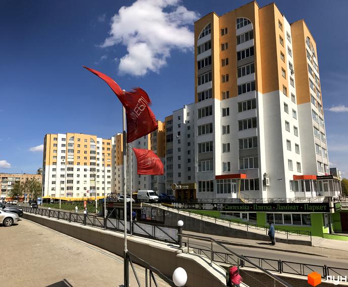 Житловий комплекс на вул. Зарічанська, 9 – це багатоповерхові будинки з яскравим фасадом та великою кількістю вікон. Навколо комплексу розташовані дороги та тротуари.