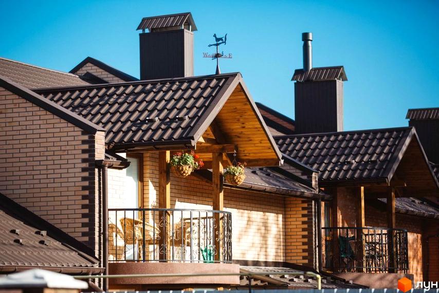 Котеджне містечко Sun House: цегляні фасади та коричневі черепичні дахи. Балкони з кованими перилами та квітковими кашпо.