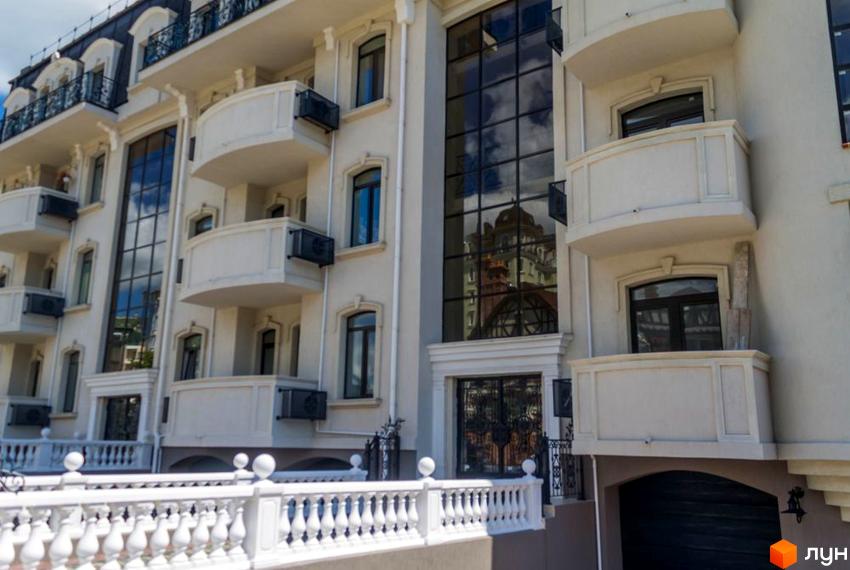 Зовнішній вигляд новобудови ЖК Palais Royal (Зелений Мис) з балконами та великими вікнами. Біла огорожа перед фасадом будівлі.