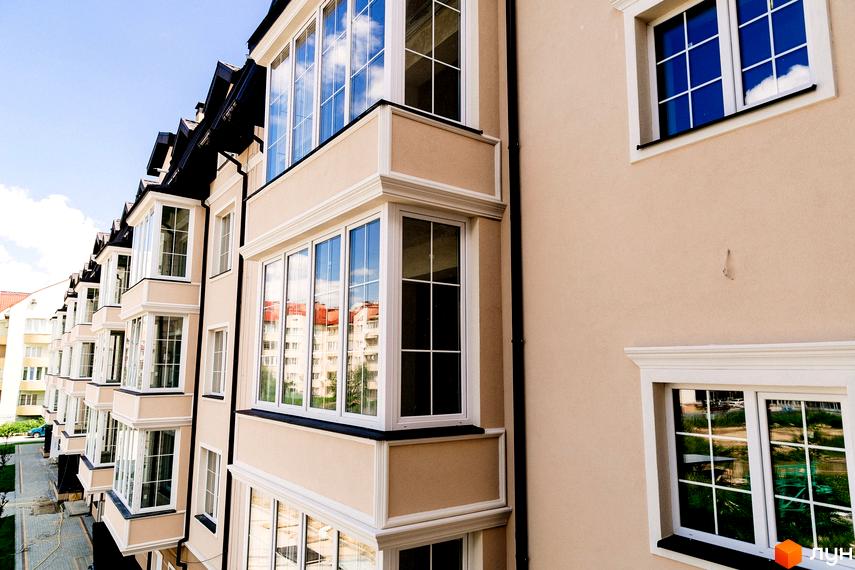 Житловий комплекс Маєток Боздош з панорамними вікнами та світлим фасадом. На фото видно частину фасаду будівлі з балконами та вікнами, а також відображення неба.