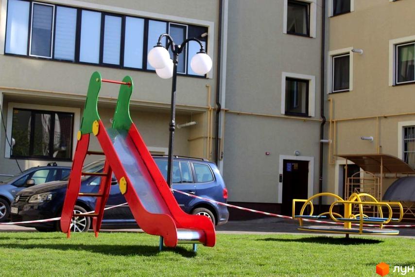 Зовнішній вигляд будинку на вул. Довга, 20в. На прибудинковій території дитячий майданчик з гіркою та каруселлю.