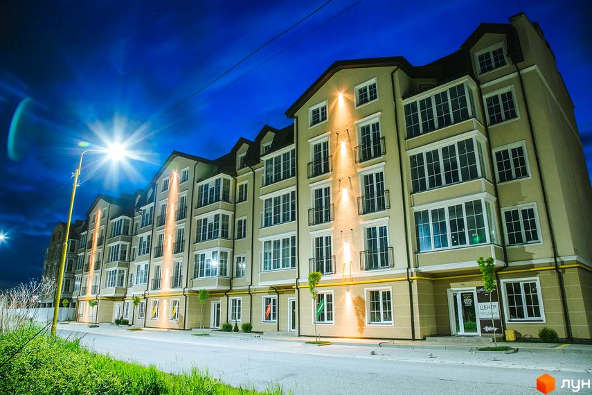 Житловий комплекс Маєток Боздош з фасадом пісочного кольору та великими вікнами. На території є асфальтована дорога та зелені насадження.