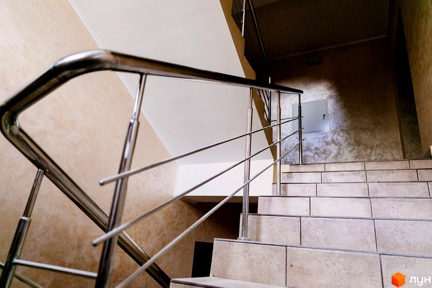 Сходи в ЖК Маєток Боздош. Сходи з нержавіючими поручнями, облицьовані світлою плиткою. На стінах - декоративна штукатурка.