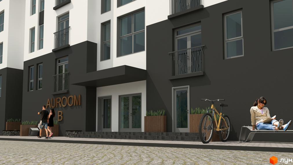 Фасад будинку житлового комплексу AUROOM B з темним кольором стін та балконами. На території біля будинку розташована лавка, велосипед та зелені насадження.