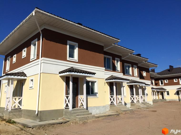 Таунхауси „Плюс“ – двоповерхові будинки з коричневими та жовтими фасадами, білими вікнами та дахами. Навколо новобудов – територія з піском та будматеріалами.