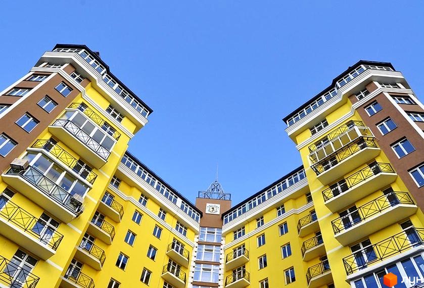 Житловий комплекс Велесгард: яскраві жовті та коричневі фасади будівель з численними балконами під чистим блакитним небом.