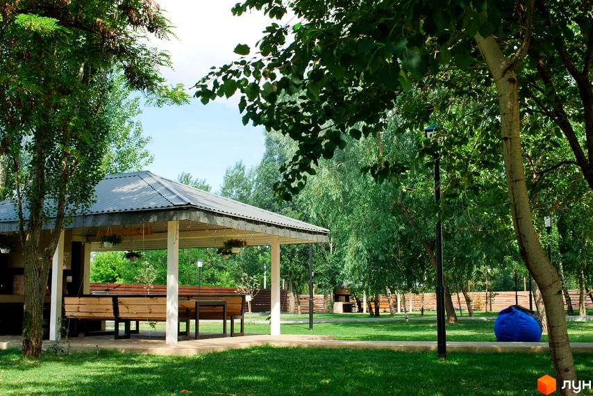 Зона відпочинку з альтанкою та лавками в ЖК Білий Шоколад. Center. Зелена прибудинкова територія з деревами та газоном.
