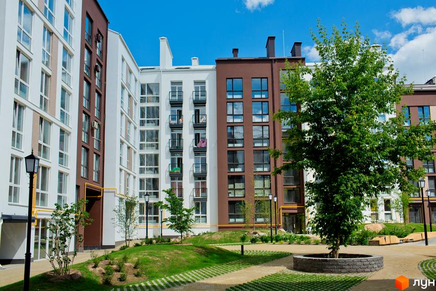 Житловий комплекс Білий Шоколад. Center. Сучасні фасади будівель з коричневими та білими елементами, великими вікнами та балконами. Прибудинкова територія з зеленими насадженнями, газоном та доріжками.