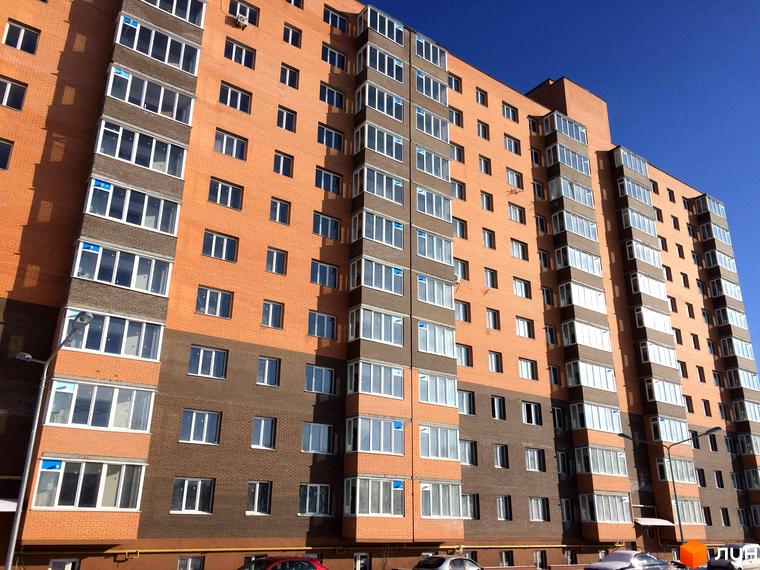 Фото фасаду багатоповерхового будинку в Житловому районі Перший Парковий квартал. Вигляд новобудови з вікнами та балконами на тлі синього неба.