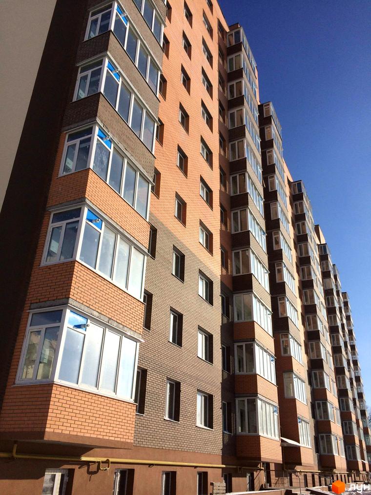 Зовнішній вигляд багатоповерхового будинку в Житловому комплексі Перший Парковий квартал. Фасад з вікнами та балконами, блакитне небо.