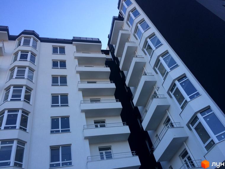 Фасад житлового комплексу Kaiser з білими стінами та великою кількістю вікон. Будинок має багато балконів та виступаючих елементів.