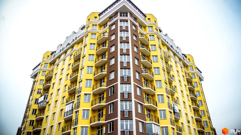 Житловий комплекс Велесгард: яскрава жовто-коричнева новобудова з балконами. Зовнішній вигляд будинку та вікна.