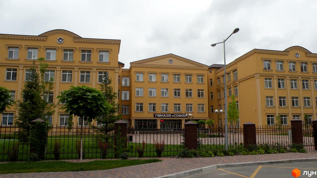Житловий комплекс Софія Сіті. Фасад жовтого кольору, багато вікон. Прибудинкова територія з огорожею та деревами.